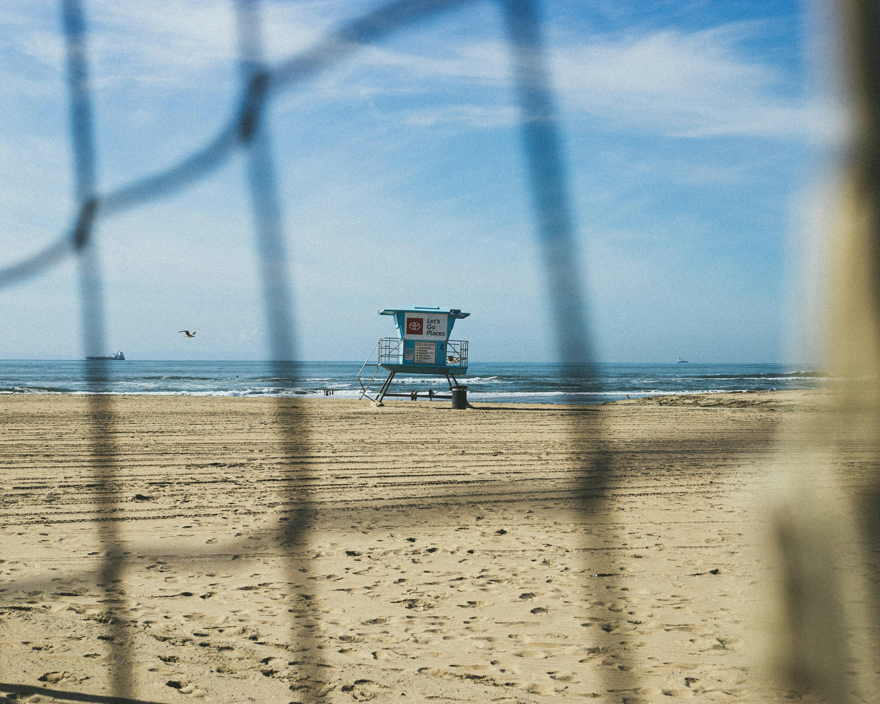 Ein Rettungsschwimmer steht am Strand hinter einem Zaun