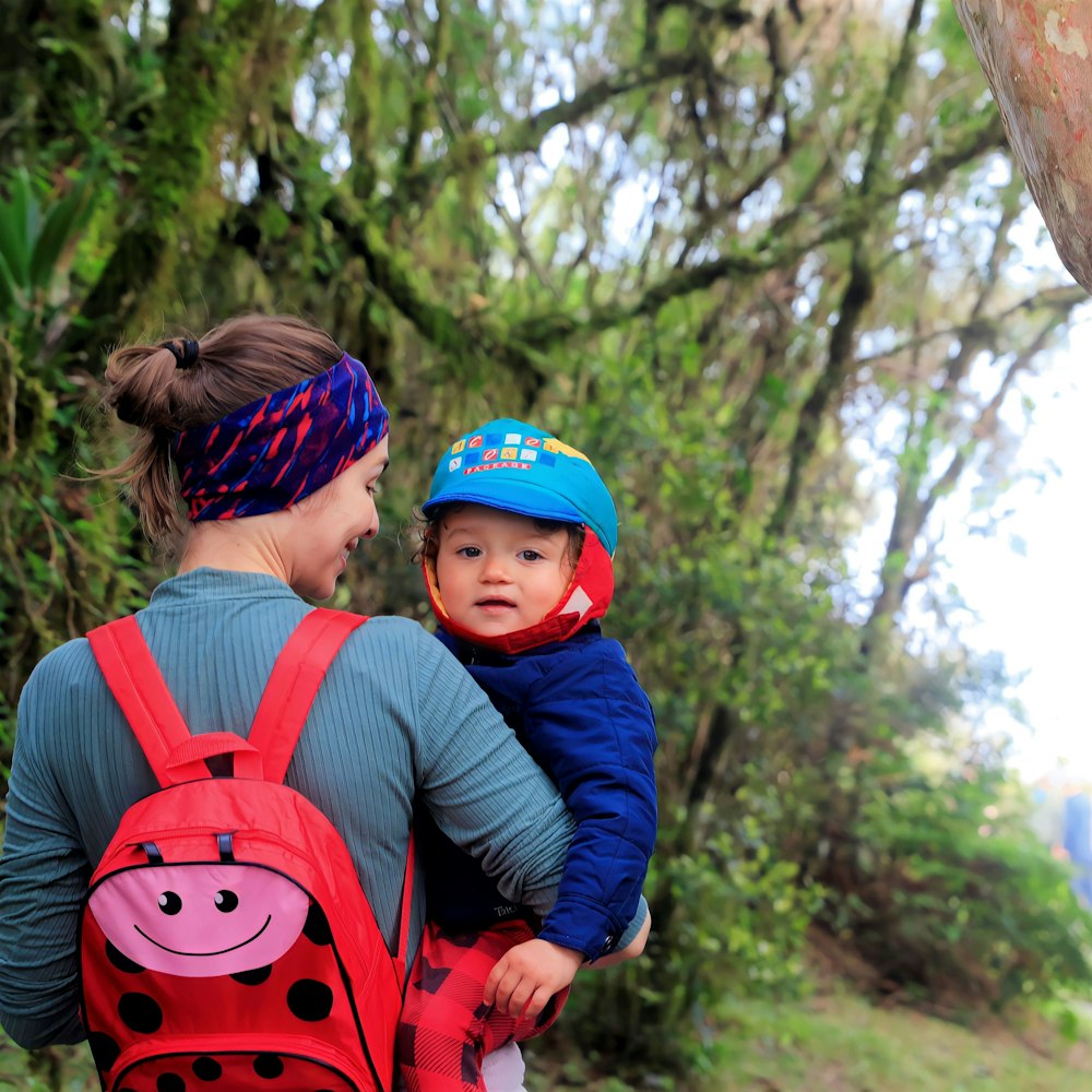 a woman carrying a child in a red backpack