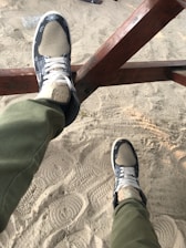 Close-up of a pair of casual espadrilles resting on a sunlit wooden bench outdoors.