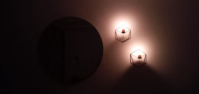 Elegant black metal wall sconce casting soft light beside a bathroom vanity mirror.