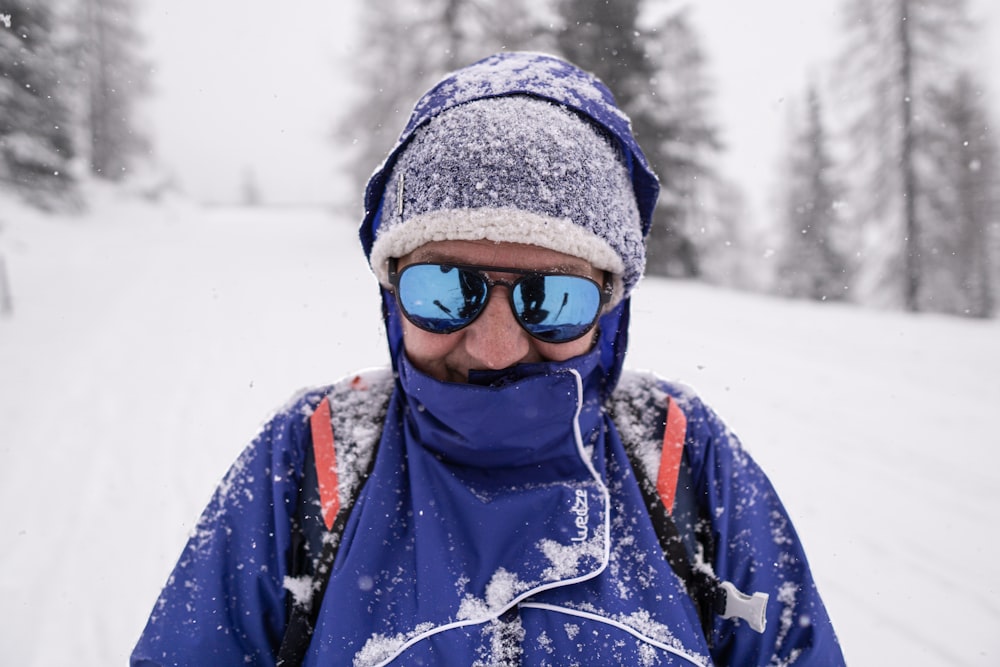 a man wearing sunglasses and a blue jacket in the snow
