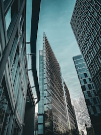Tall modern buildings with reflective glass facades surrounded by an overcast sky. The architectural design is sleek and contemporary, creating a sense of urban development.
