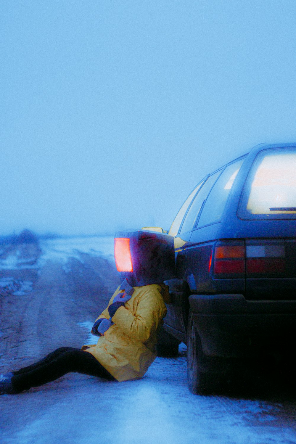 a person laying on the ground next to a car