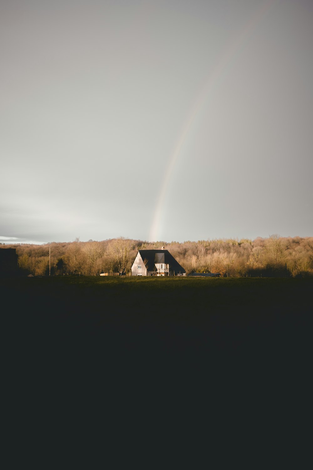 a house in a field with a rainbow in the background