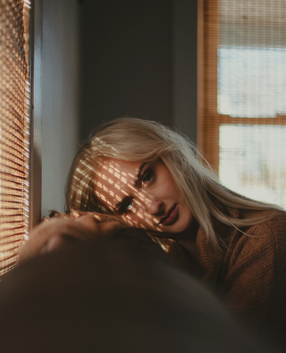 a woman with blonde hair is looking out a window