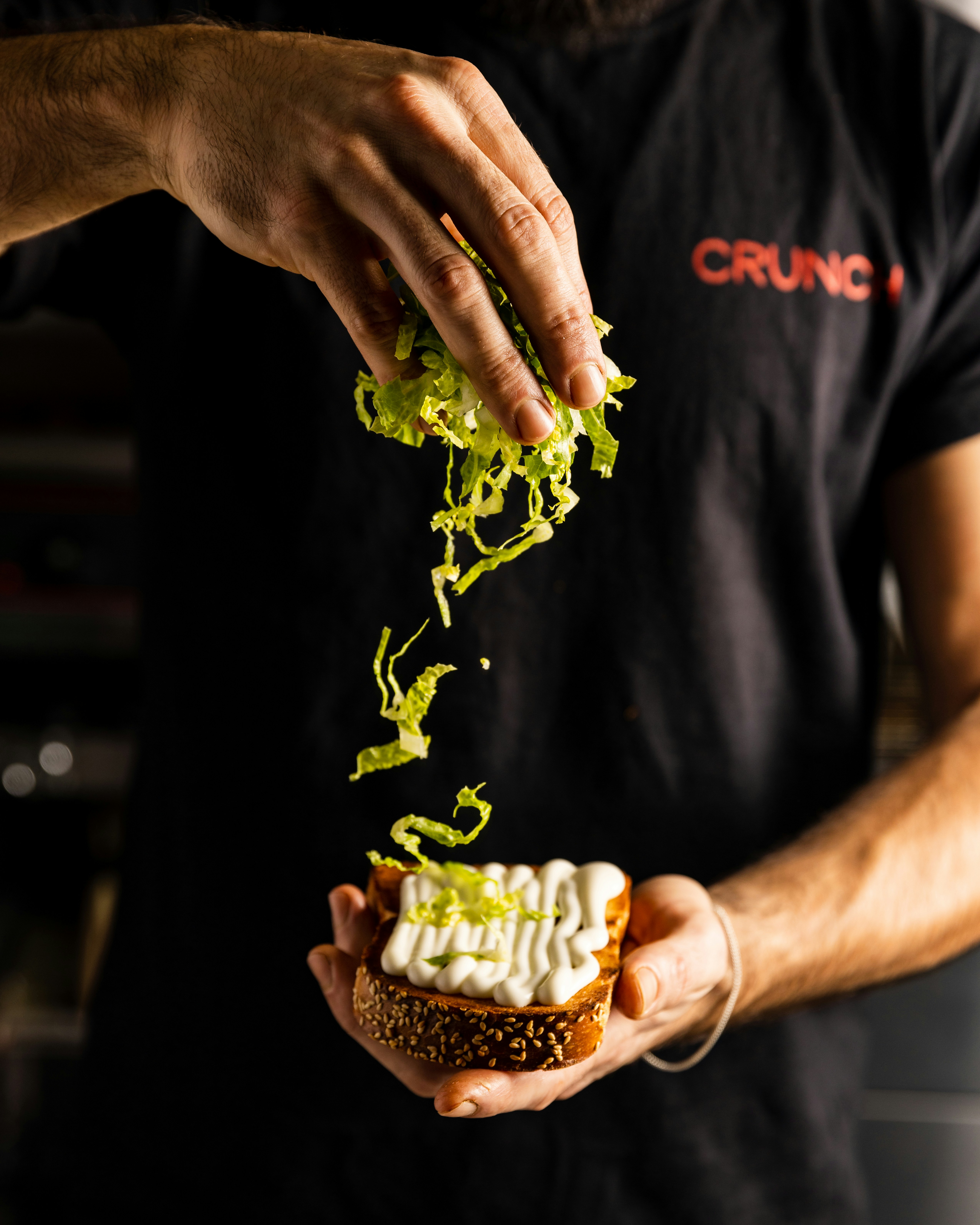 a man holding a sandwich with lettuce and mayonnaise