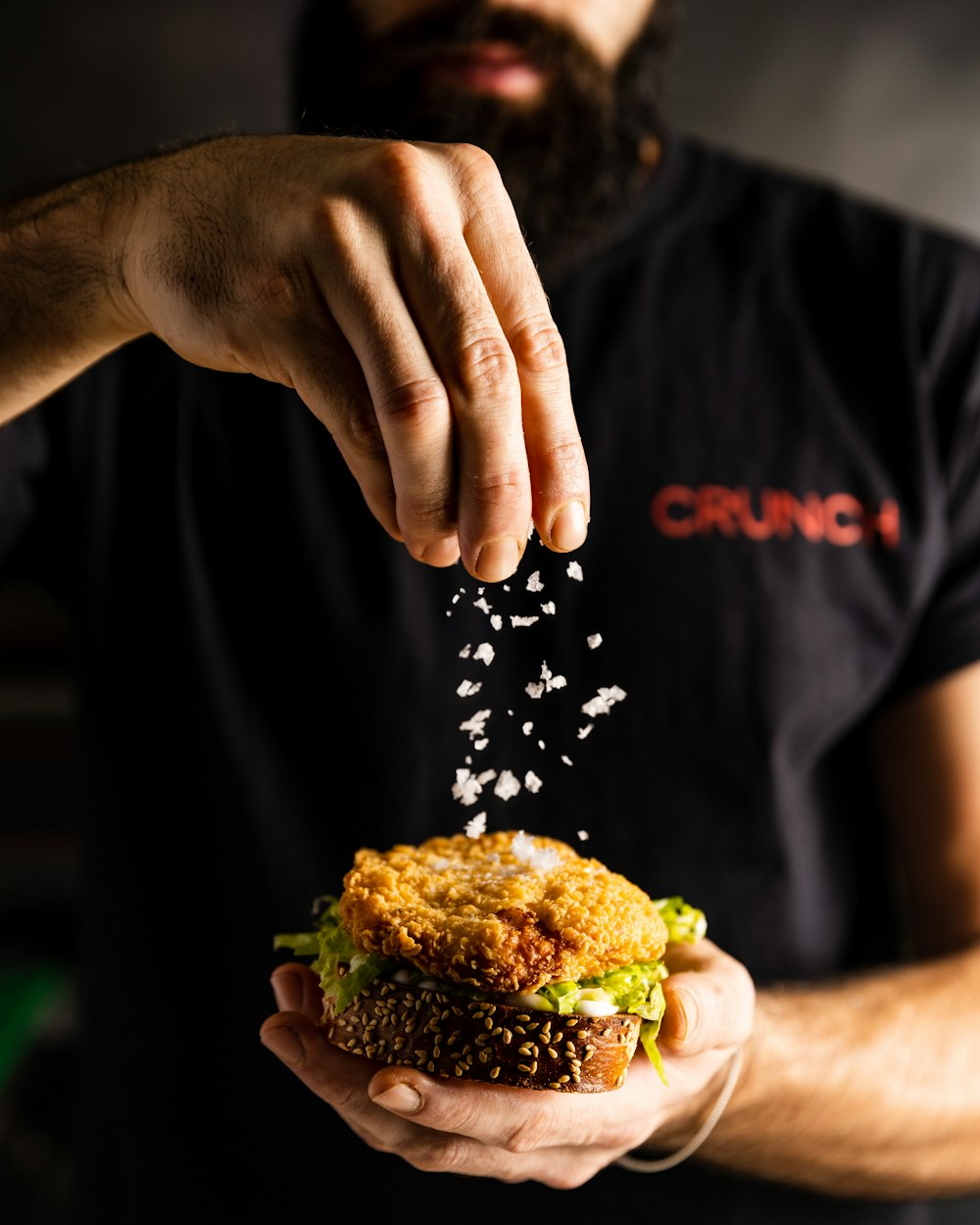 Un homme saupoudre des graines sur un sandwich