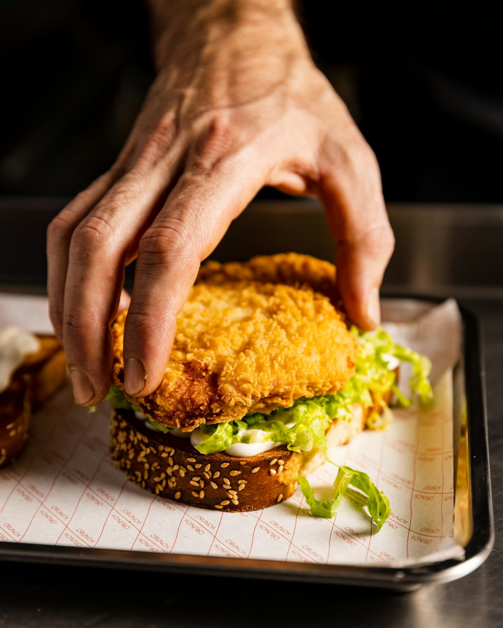 a person reaching for a fried chicken sandwich