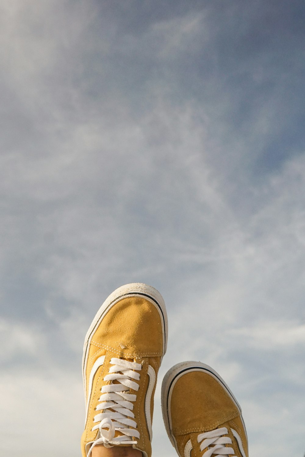 die Füße einer Person mit gelben Schuhen, die auf einem Felsvorsprung stehen