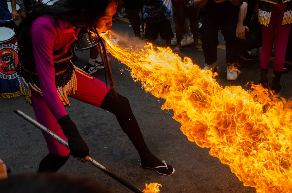 a woman in a red outfit is holding a stick with flames coming out of it