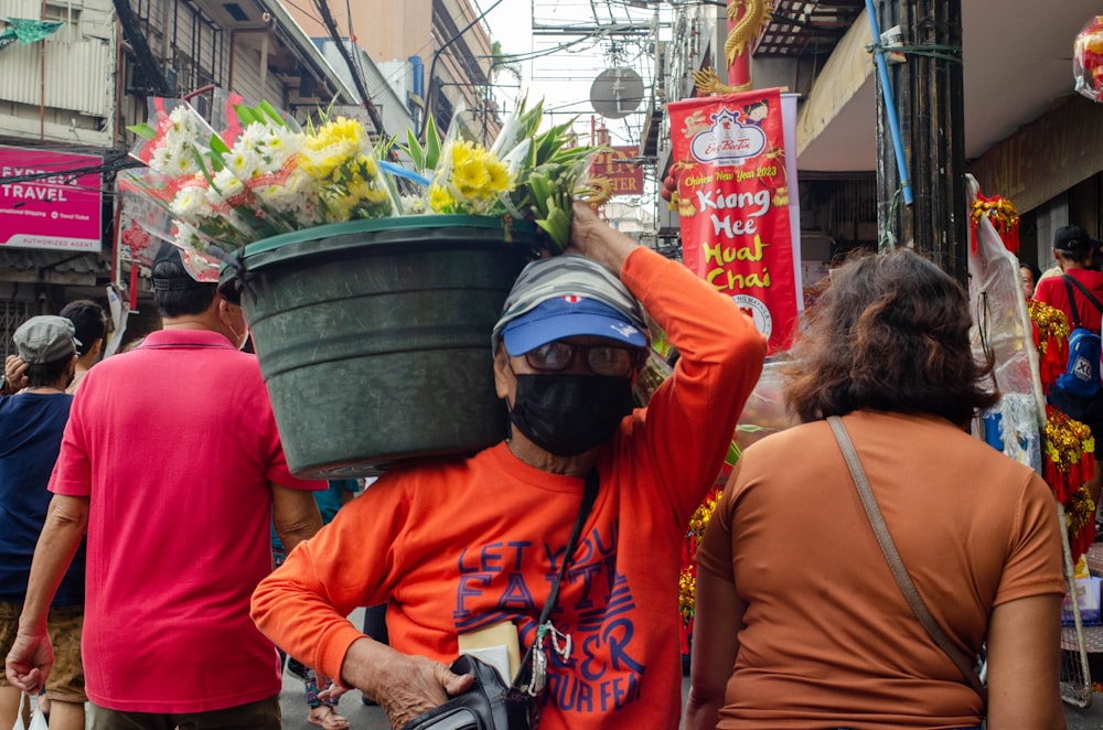 a man with a bucket of flowers on his head