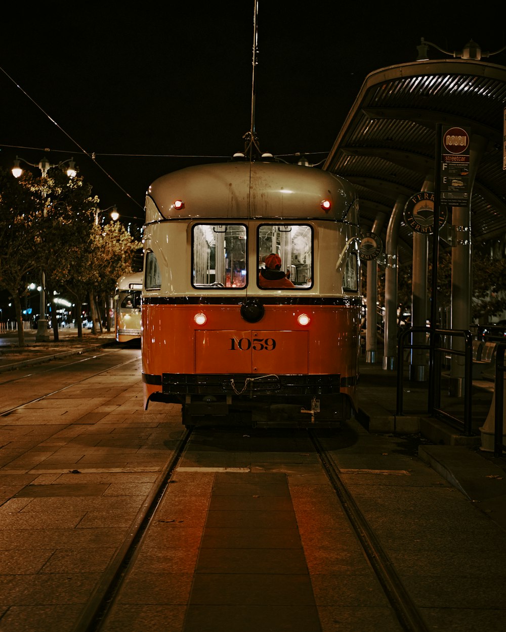 an orange and white train on a track at night