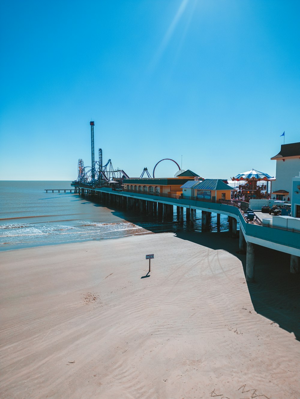 a pier on the beach with a roller coaster in the background