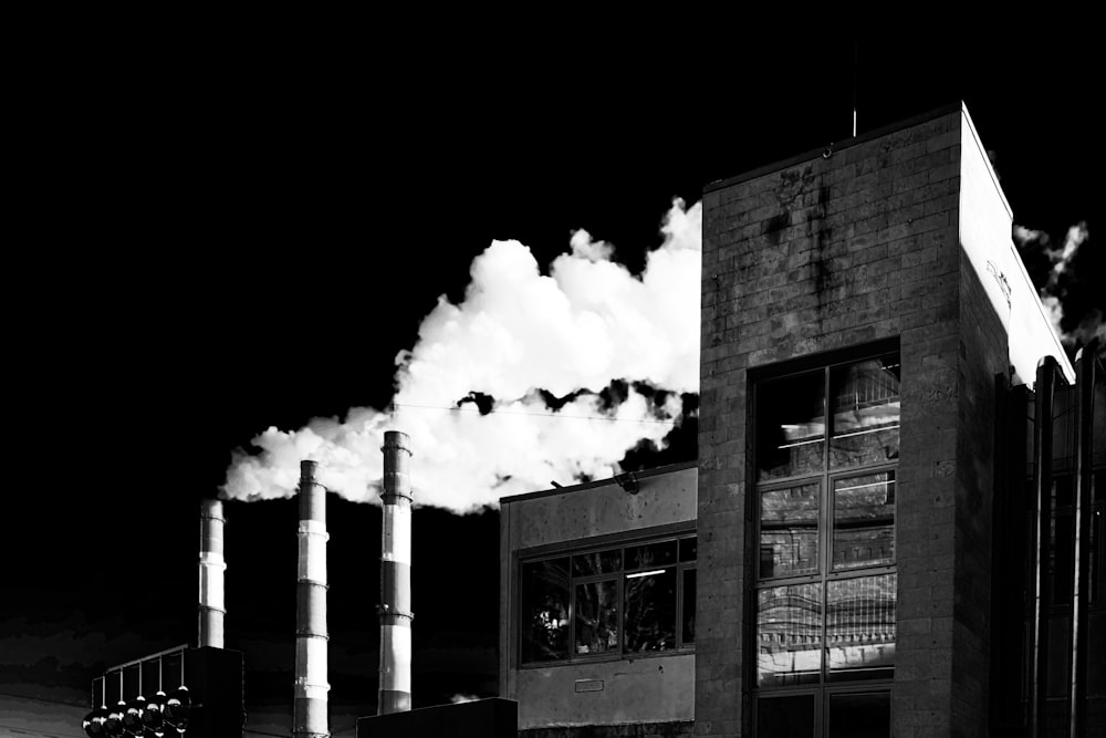 a black and white photo of smoke coming out of a factory