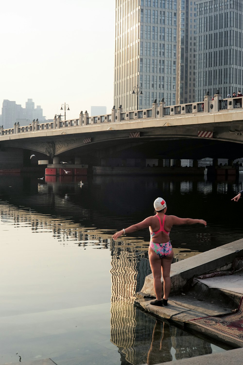 a woman in a bathing suit standing on a dock next to a body of water