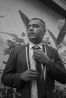 Groom adjusting his tie, framed by rustic wooden doors.