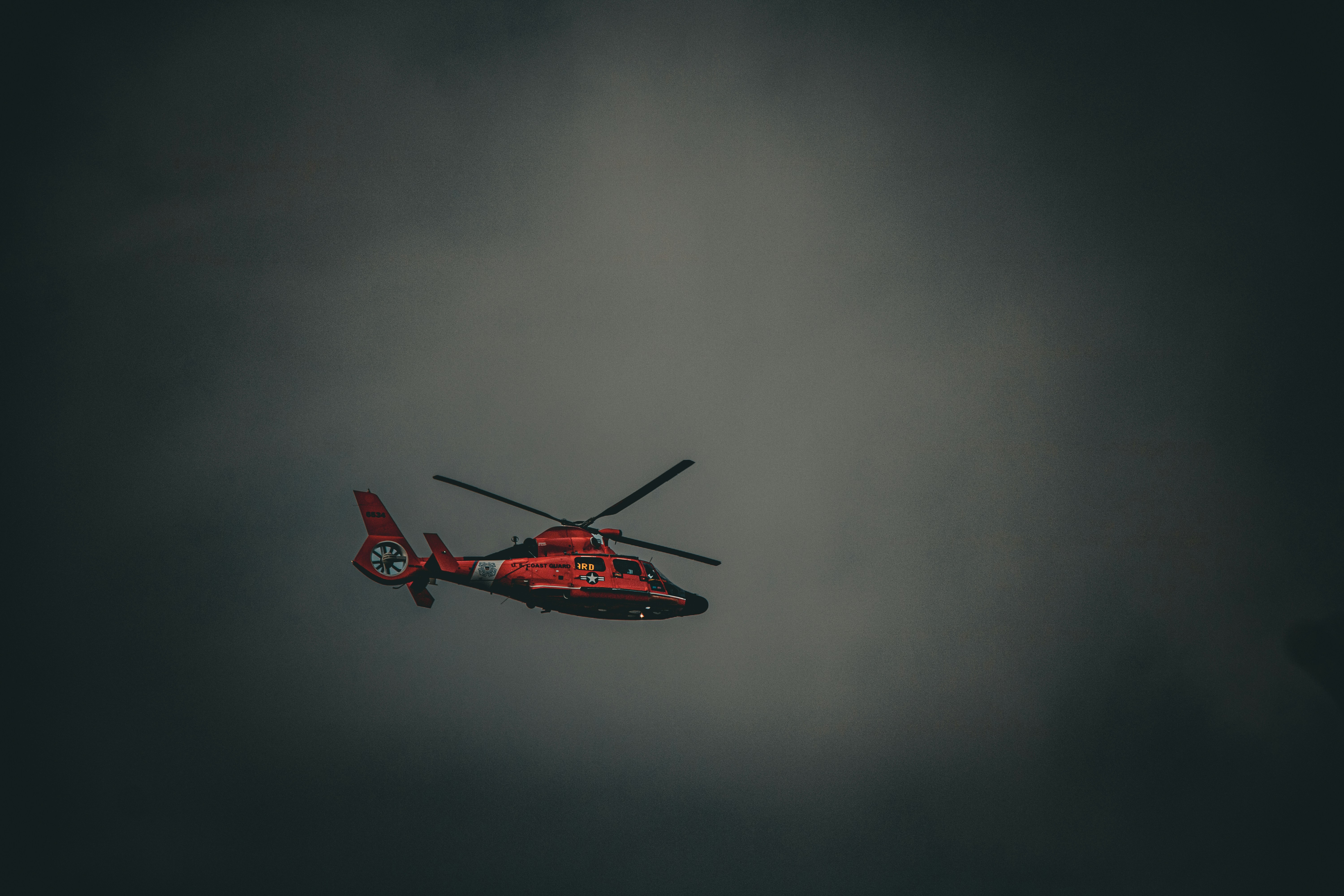 a red helicopter flying through a cloudy sky