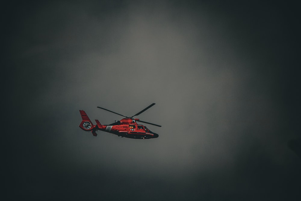 Un helicóptero rojo volando a través de un cielo nublado