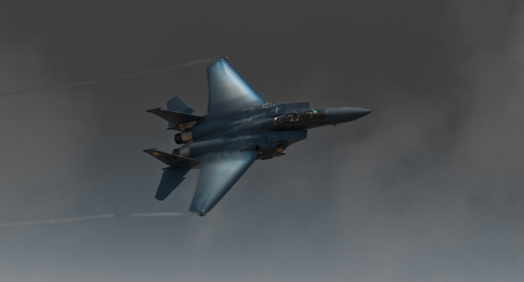 a fighter jet flying through a cloudy sky,