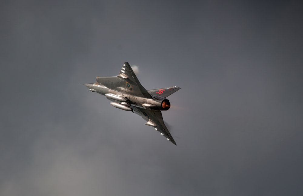 a fighter jet flying through a cloudy sky