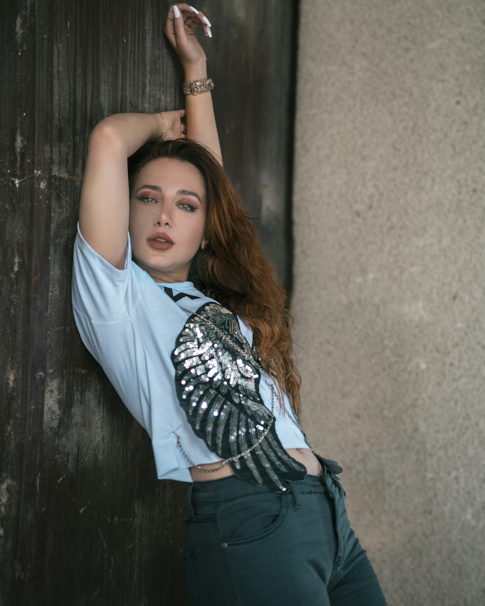 a woman leaning up against a wall with her hand on her head