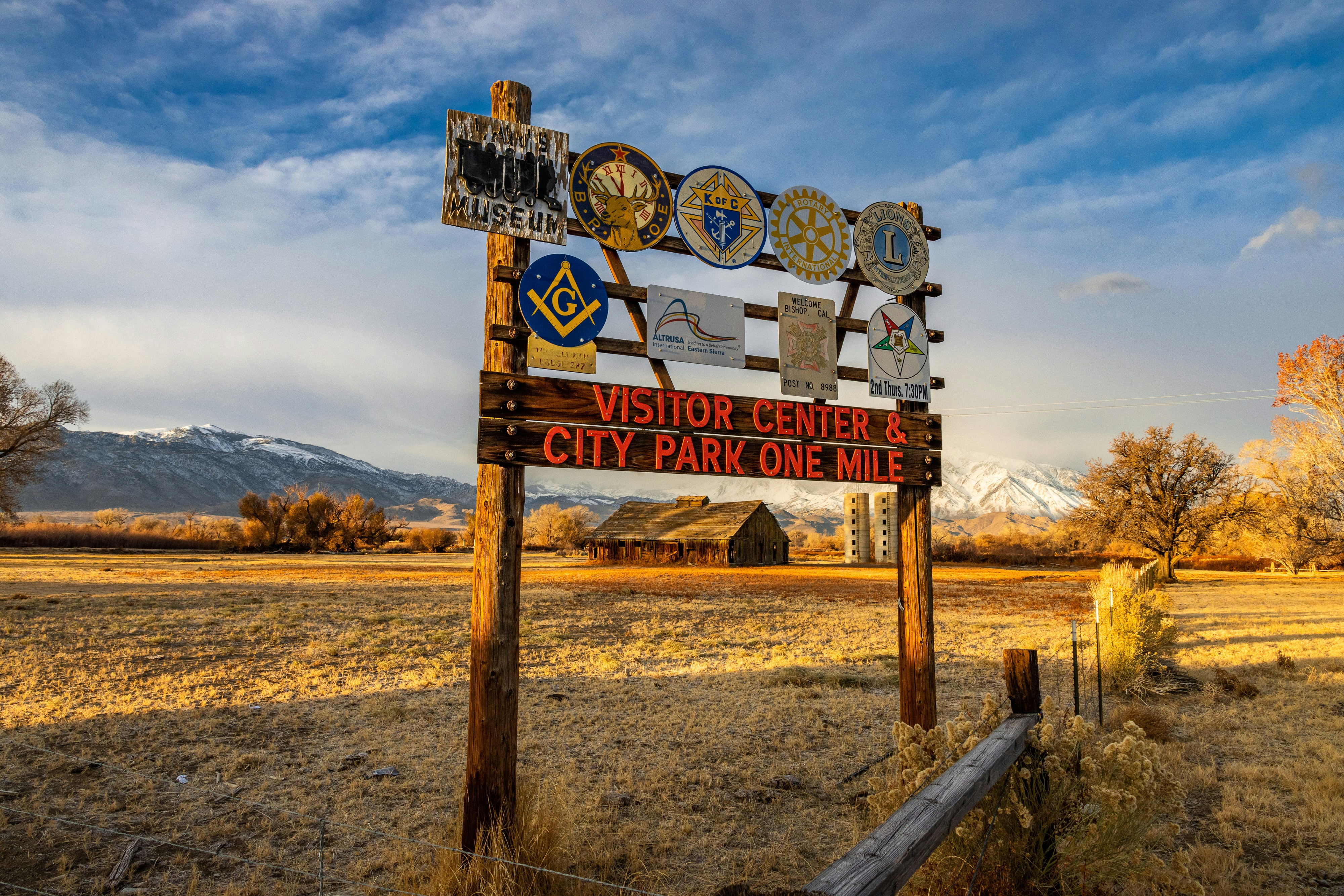 ein Schild mitten auf einem Feld mit Bergen im Hintergrund