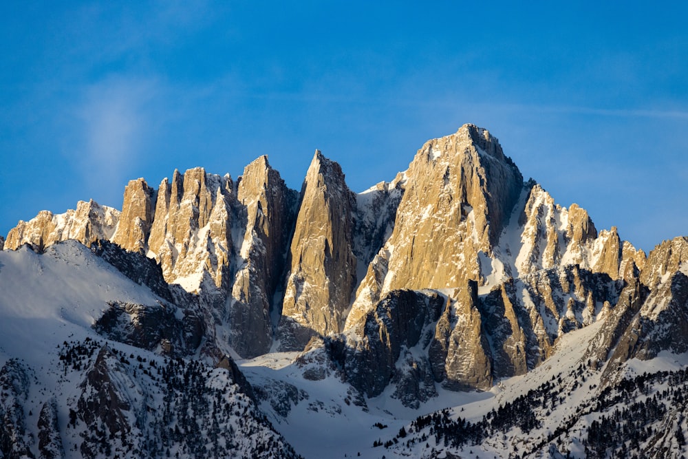 a mountain range covered in snow under a blue sky