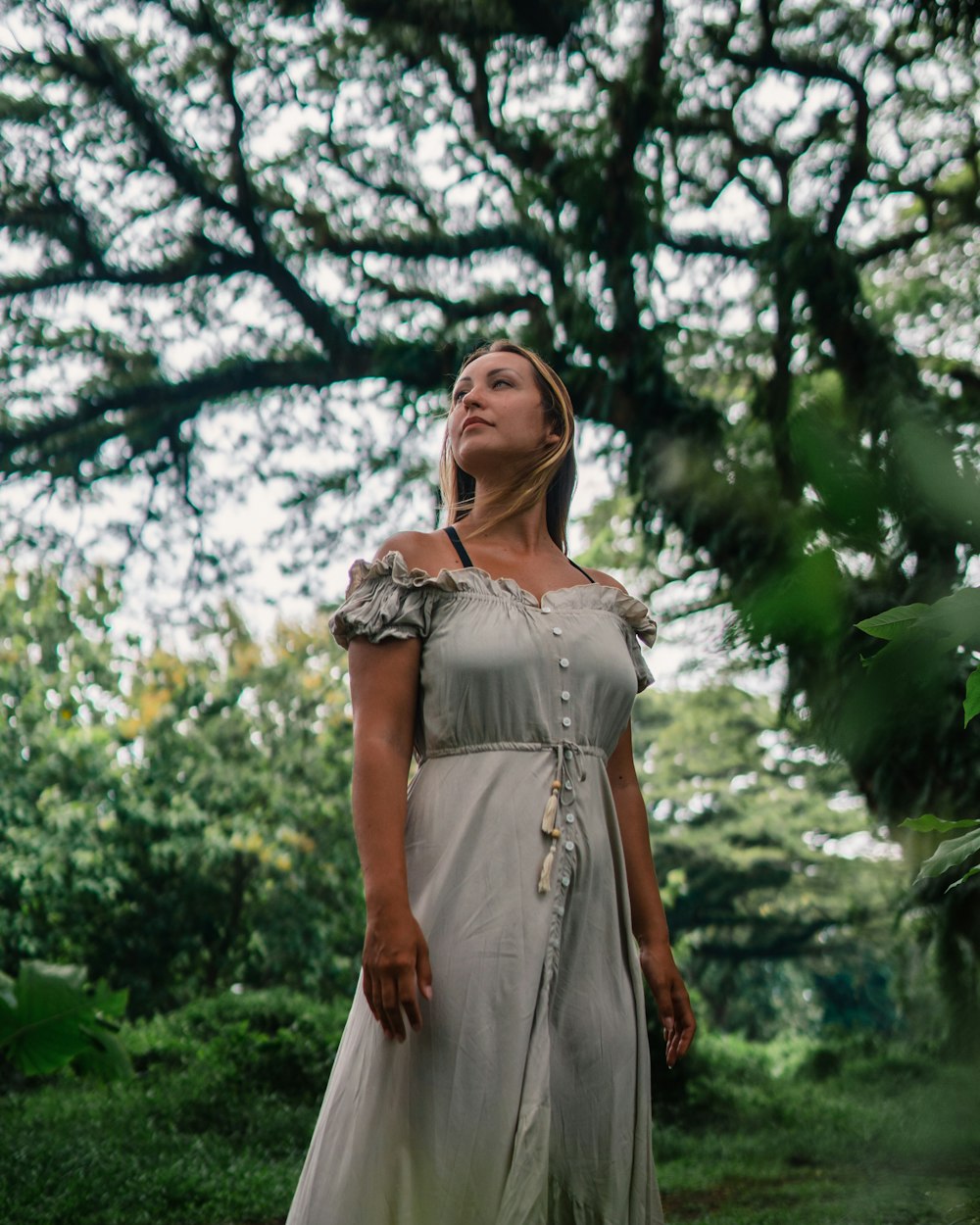 a woman in a dress standing under a tree