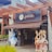 A storefront of a chocolate shop named 'Chocolataria Gramado' with a pergola-style wooden structure above. Two large plush figures resembling rabbits and a snowman stand near the entrance, adding a whimsical touch.