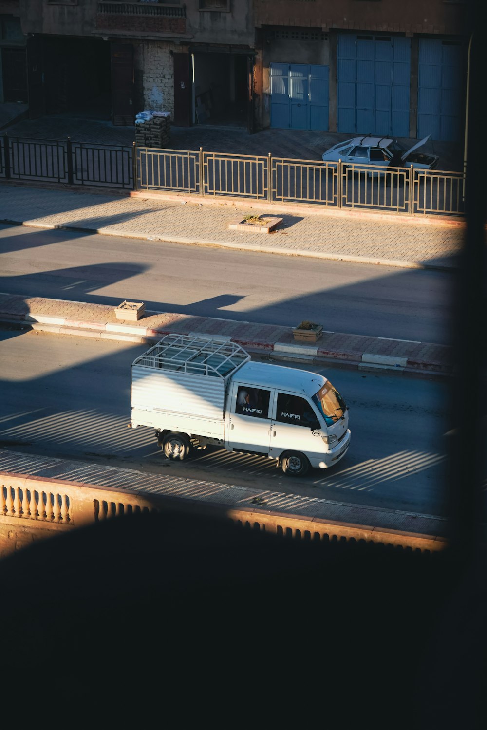 a white truck driving down a street next to a tall building