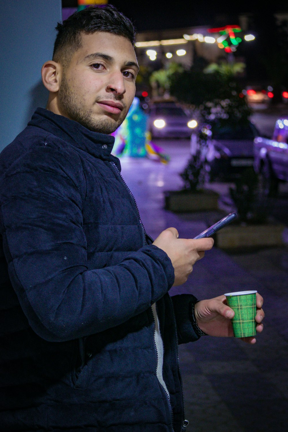 a man holding a cup and a cell phone