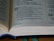 An open Bible is placed on a flat surface, displaying text from the Book of Isaiah. The visible verses include excerpts from chapter 25, which feature religious text written in both bold and regular fonts. A ribbon marker is slightly visible under the pages, and the lighting highlights the pages' texture.