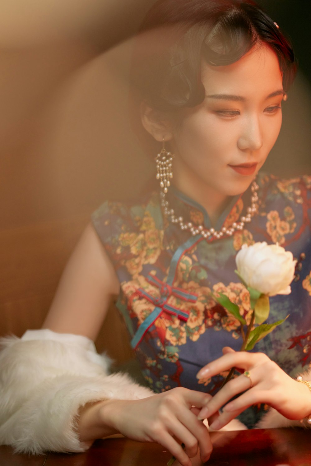 a woman sitting at a table with a flower in her hand