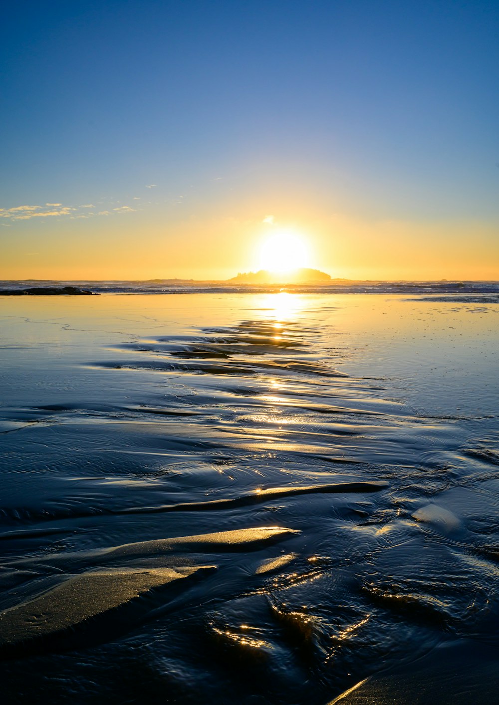 the sun is setting over the water at the beach