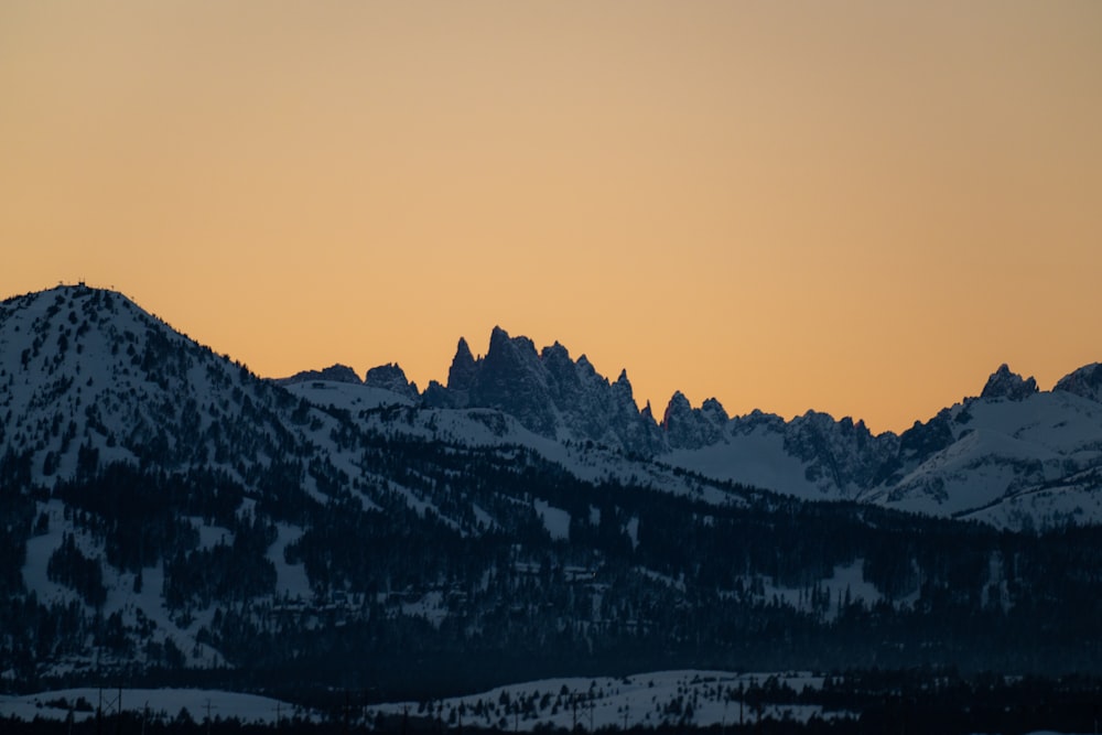 a mountain range covered in snow at sunset