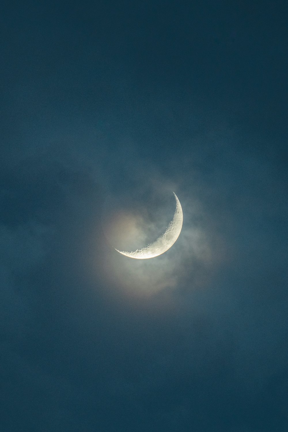 a crescent moon is seen through the clouds
