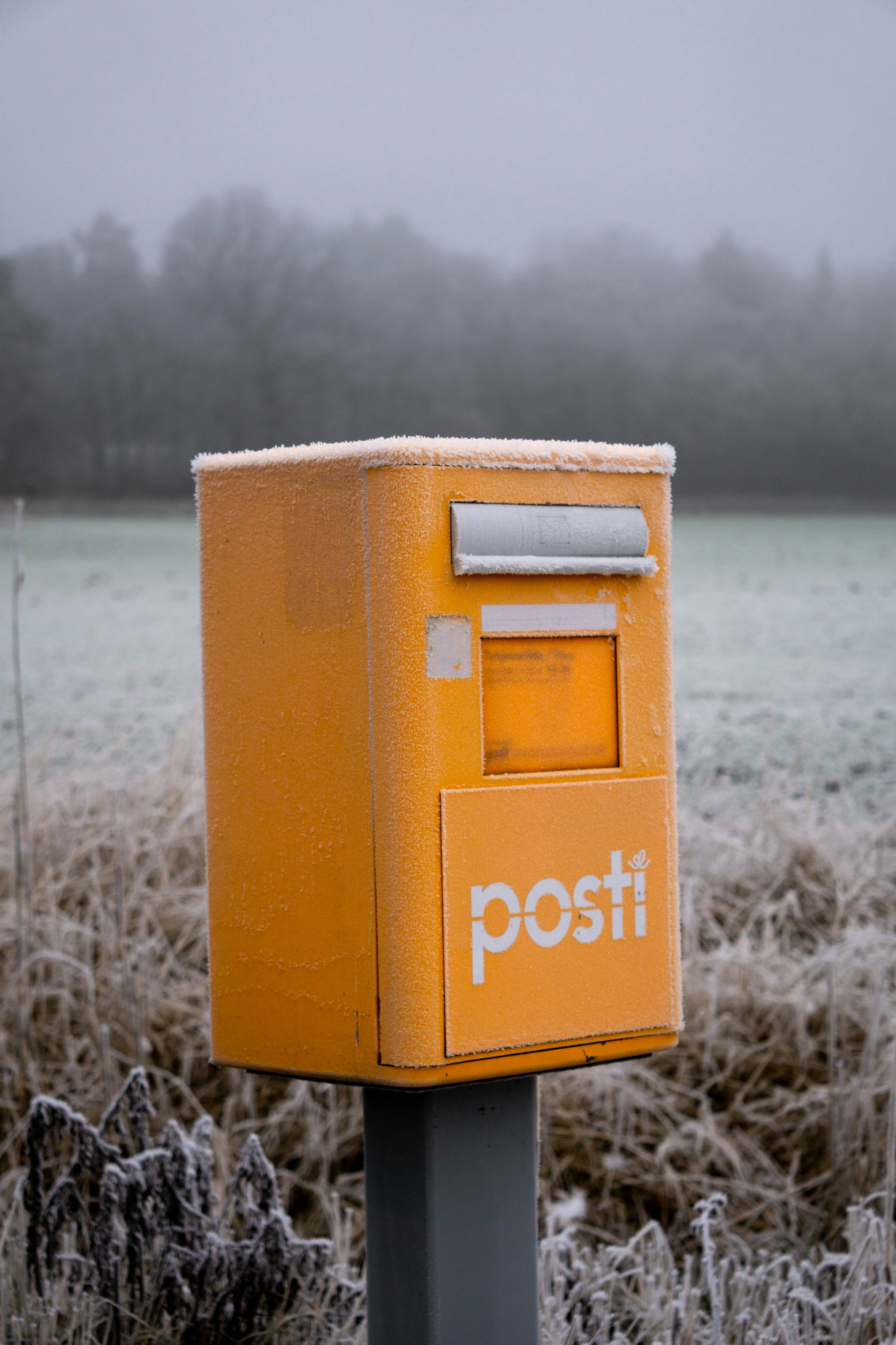 a yellow post box sitting in the middle of a field