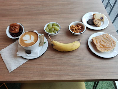 A colorful breakfast package with fresh fruits, pastries, and a coffee cup on a wooden table