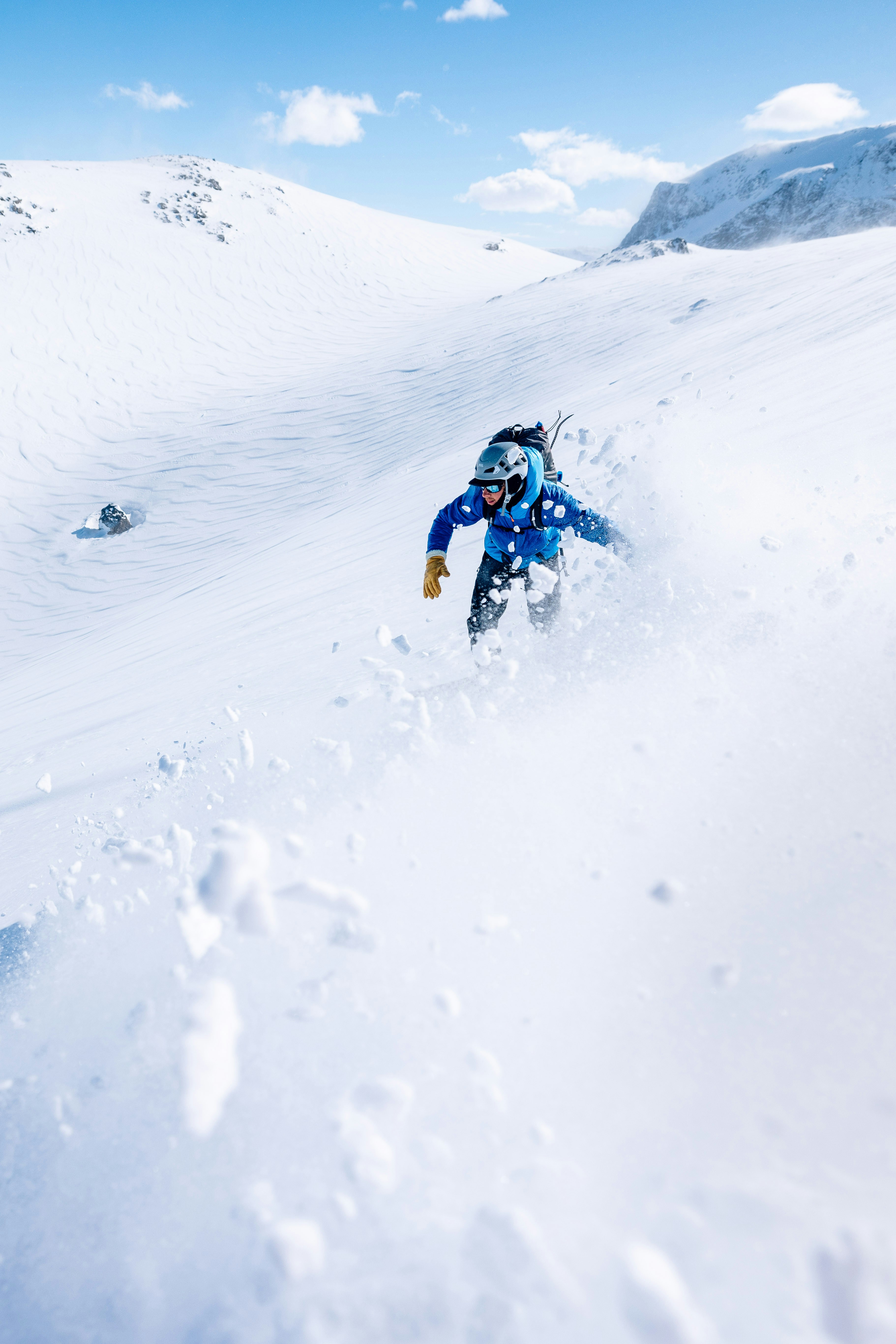 Un uomo che cavalca uno snowboard lungo il fianco di un pendio innevato