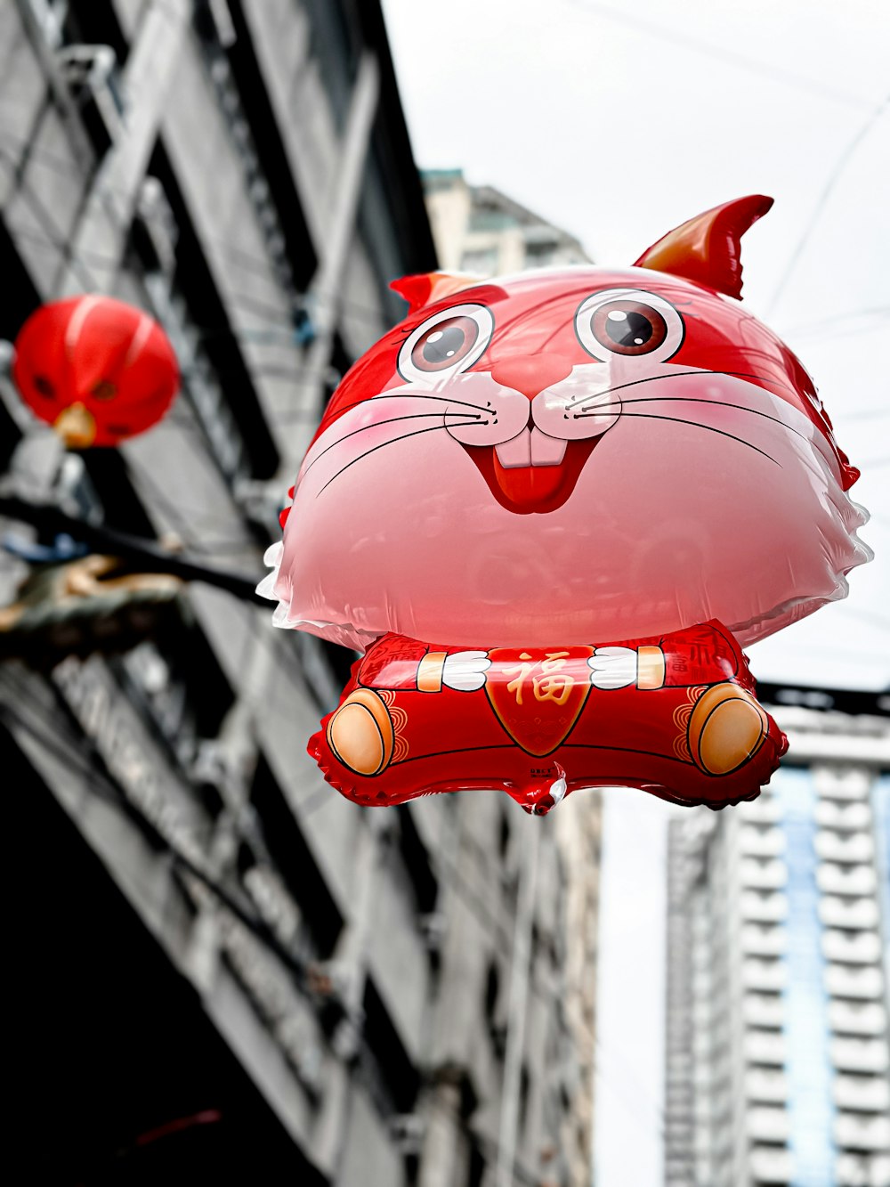 a red cat balloon hanging from the side of a building