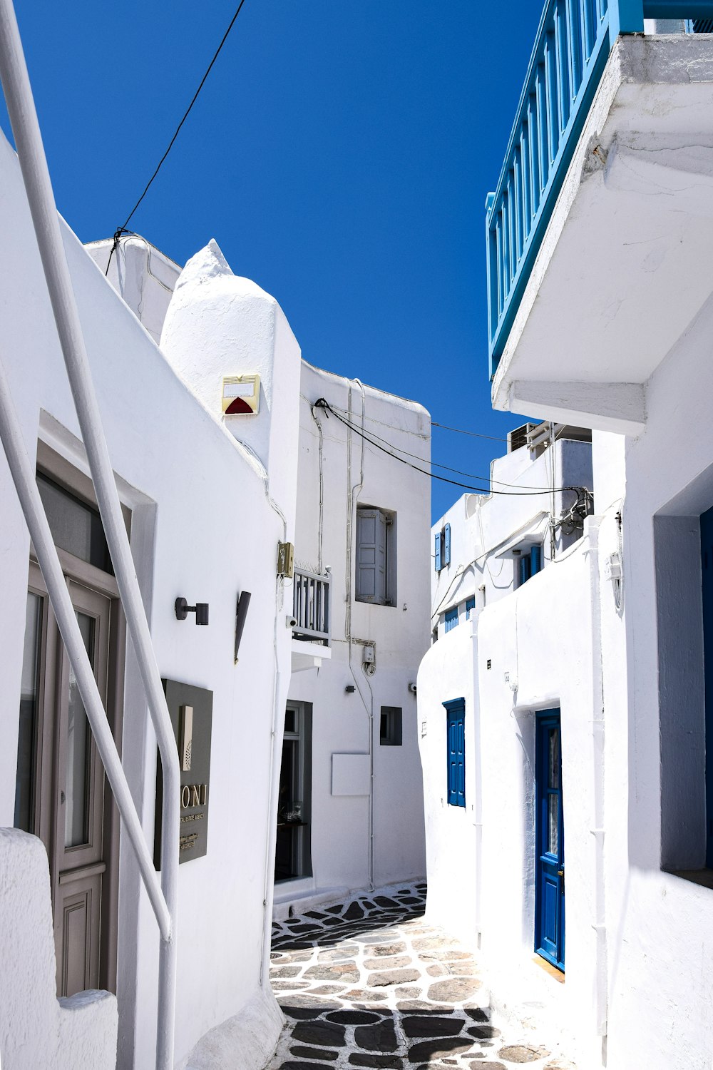a narrow street with white buildings and blue shutters