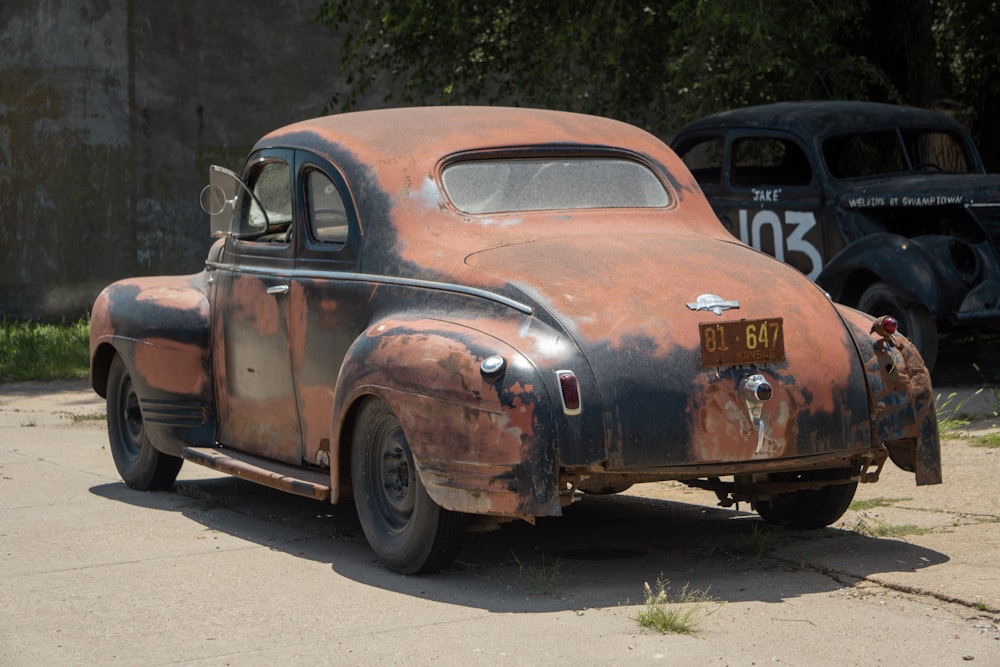 an old rusted out car sitting on the side of the road