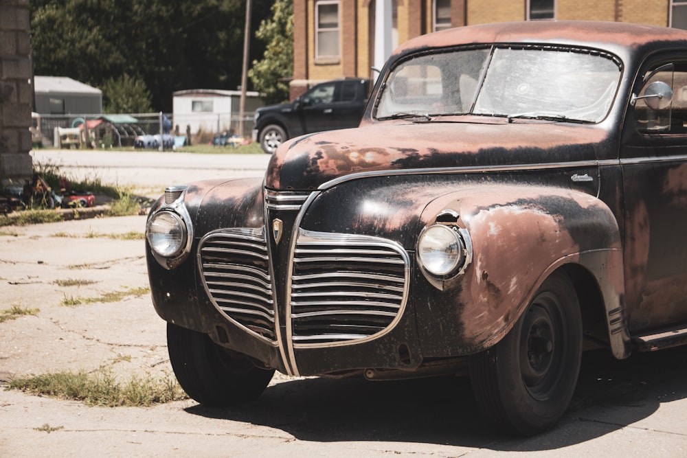 an old rusted car parked on the side of the road