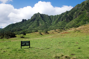 A scenic mountain landscape with a film crew setting up equipment.