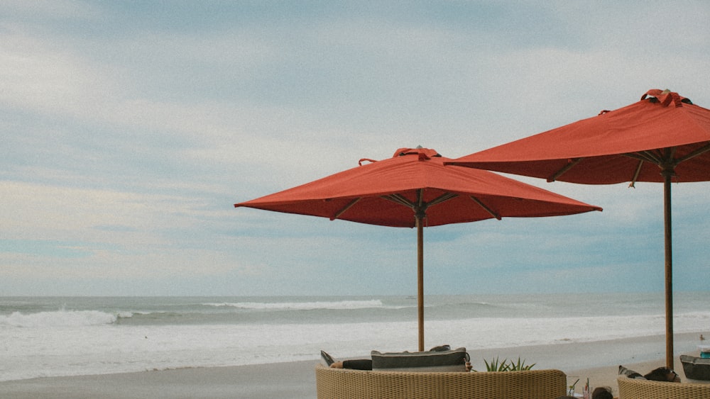 a couple of red umbrellas sitting on top of a beach