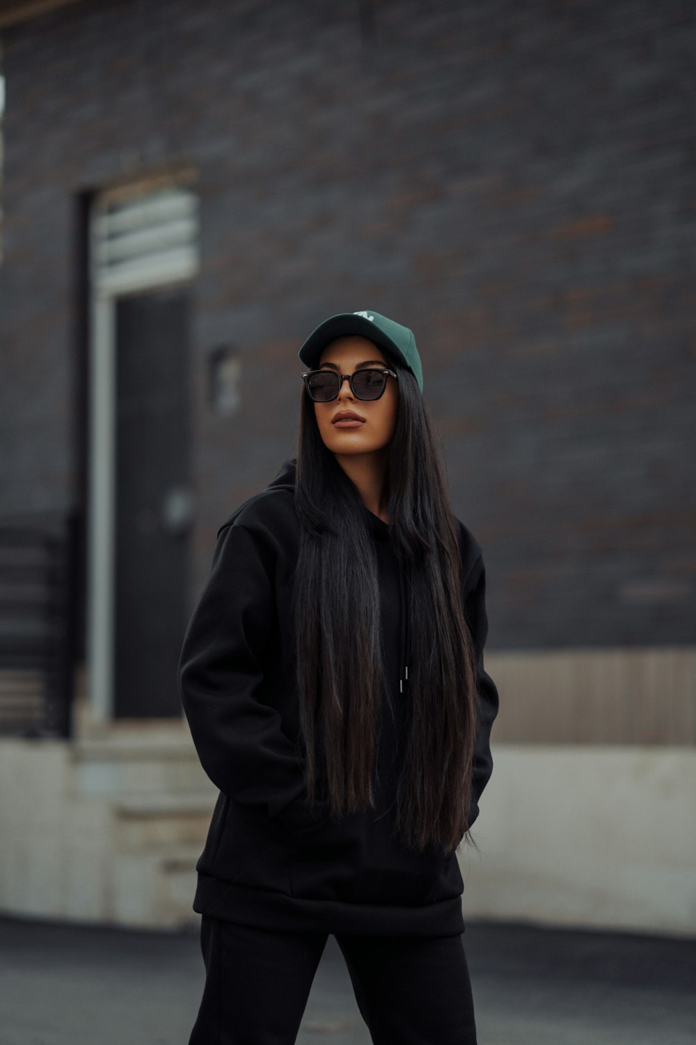 a woman with long hair wearing sunglasses and a black hoodie