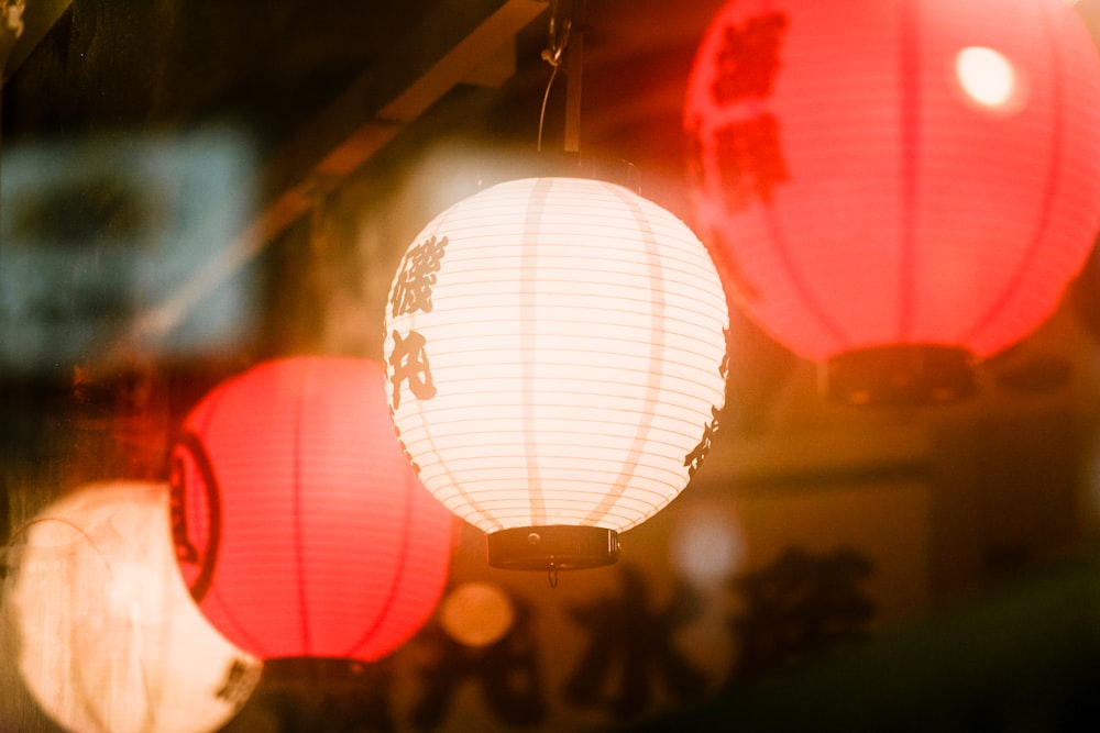 three red and white lanterns hanging from a ceiling