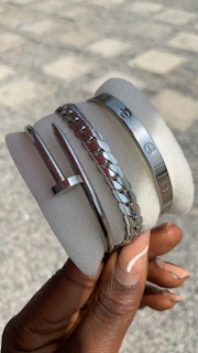 Minimalist jewelry display with rings and bracelets on a dark textured surface.