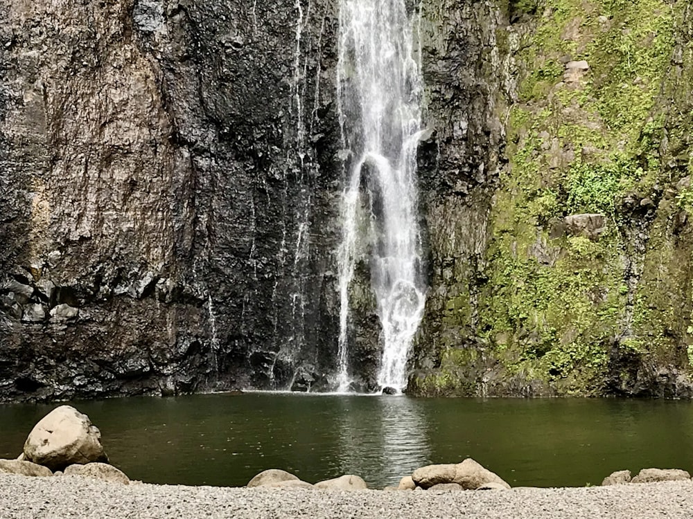 a waterfall with a man standing in front of it