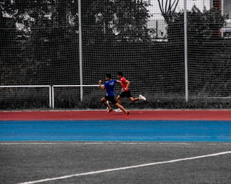 An athlete sprinting outdoors with a coach observing and timing the run.